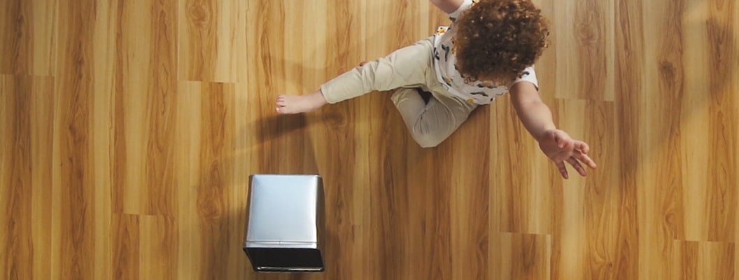 ребенок бросает металлическую коробку на кварц-виниловый пол